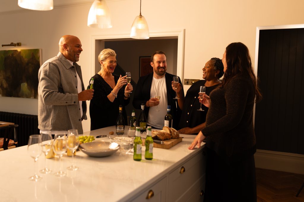 5 people laughing in kitchen celebrating