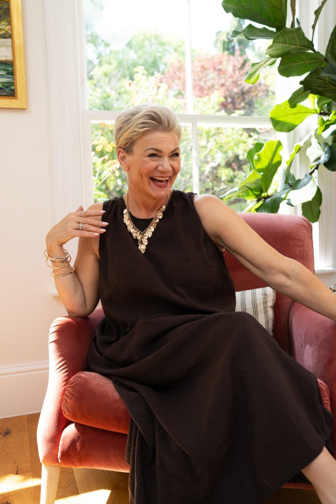 Women laughing, sat in armchair.