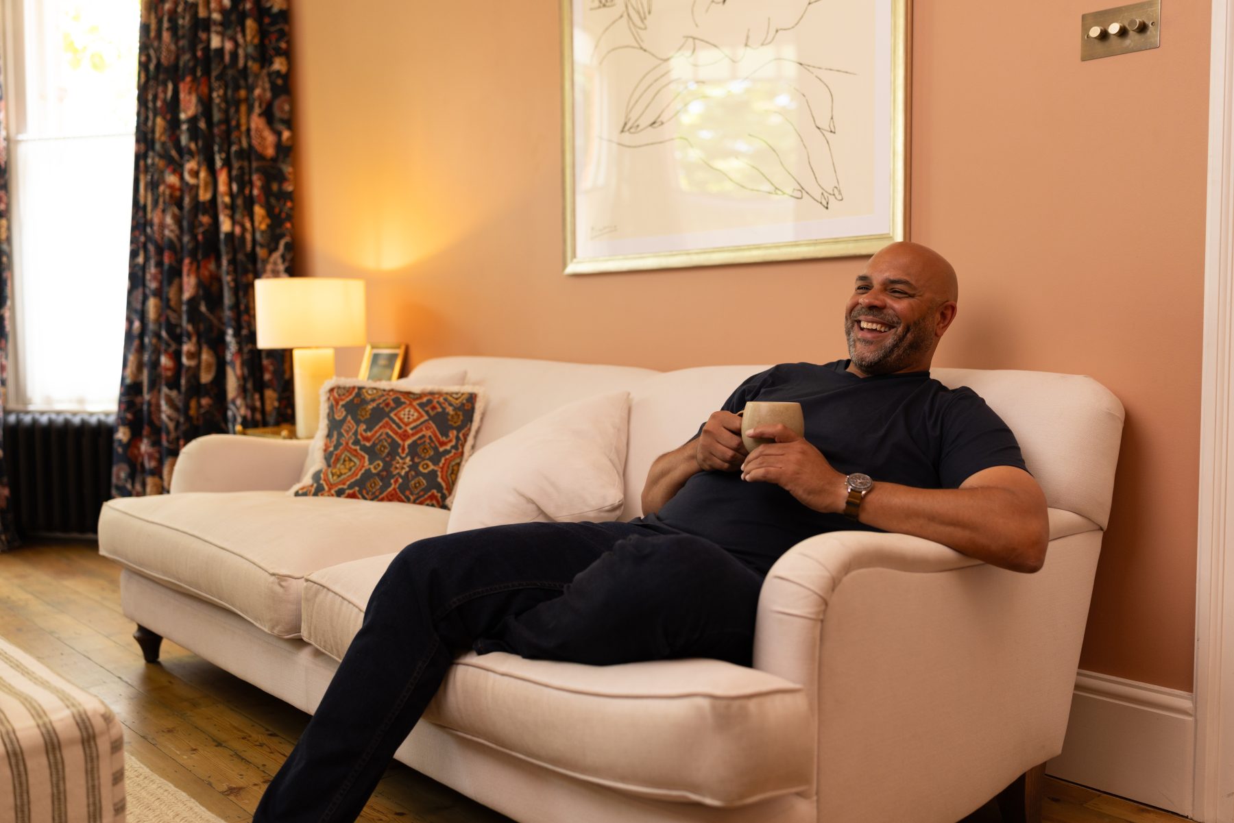 Man laughing on sofa with a cup
