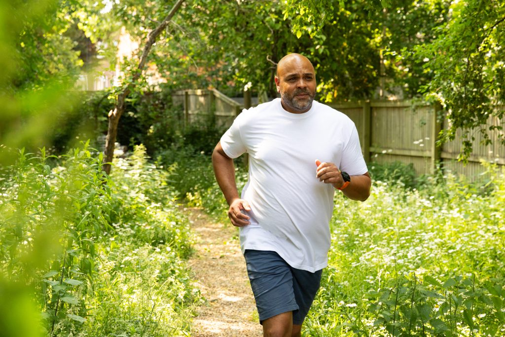 Man jogging in lush greenery.