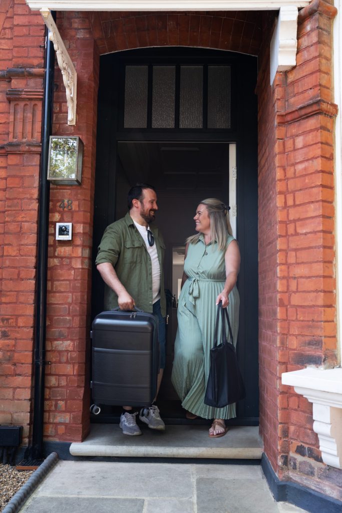 2 people holding suitcases in doorway